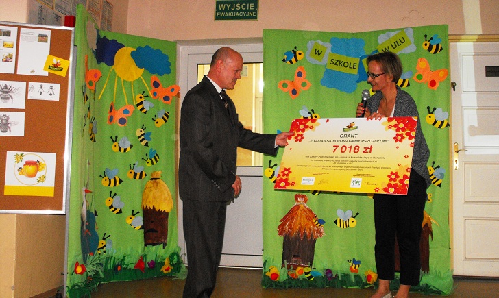 Pani Agnieszka Jastrzębska reprezentująca Zakłady Tłuszczowa Kruszwica S.A. wręcza grant na ręce Pana Henryka Grzesiak, dyrektora Szkoły Podstawowej w Hanulinie. Źródło: SP w Hanulinie.
